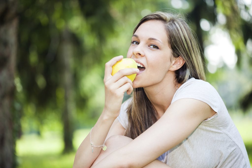 Young woman eating an apple in the park